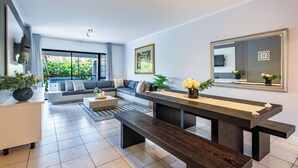 A modern living room with a sofa, a long table, and a ceiling fan. - La Pirogue, Spacious 3 Bed | Willards Beach | Pool (Dolphin Coast)
