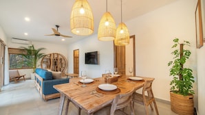A dining area with a wooden table set for four, surrounded by wicker chairs. - Tropical Villa Senang (Ungasan)