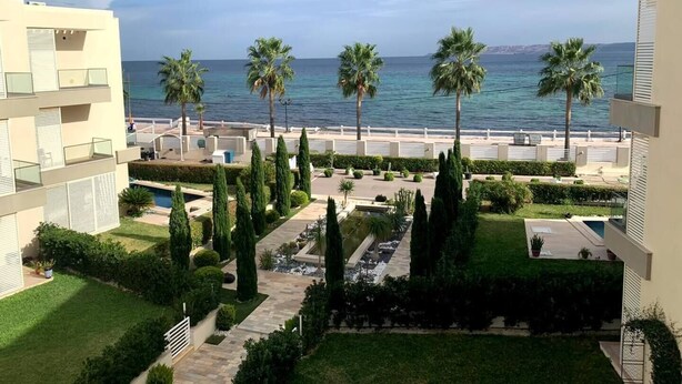 A resort with a pool, palm trees, and a view of the sea.