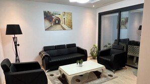 A modern living room with a black sofa set, a white coffee table, and a floor lamp.