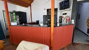 Et værelse med en rød metalbordplade, et træloft, et tv monteret på væggen og en seng med et blåt tæppe.