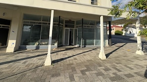 En bygning med et overdækket indgangsparti, store vinduer og en belagt grund.