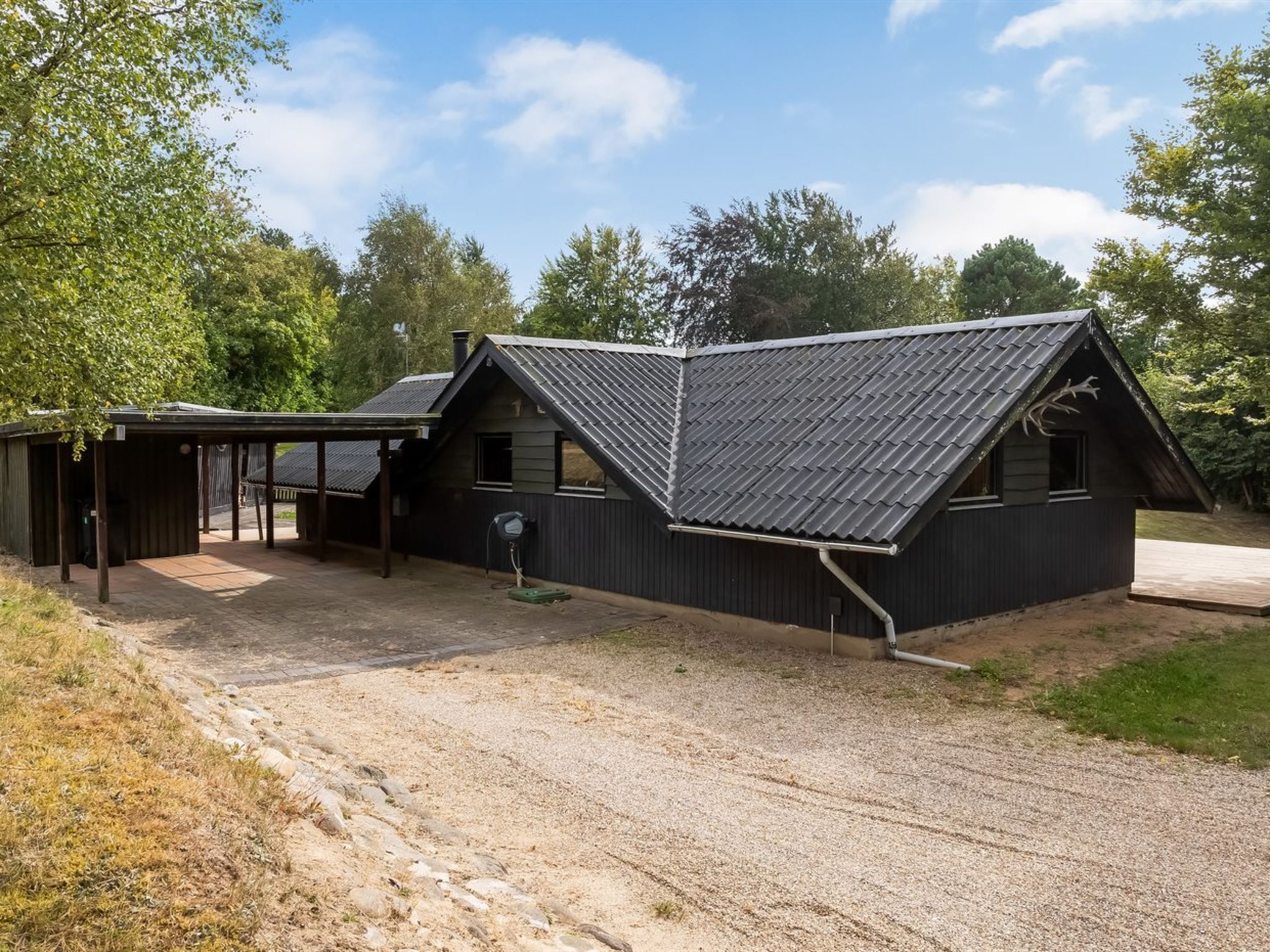 A two-story building with a sloped roof, a covered porch, and a gravel driveway.