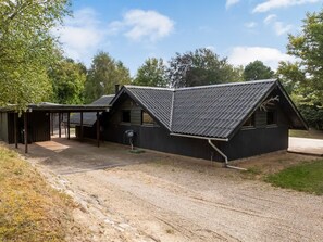 A two-story building with a sloped roof, a covered porch, and a gravel driveway.