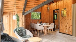 Un interior de madera con una zona de comedor, una planta colgante y un cuadro en la pared.