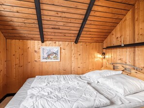 A wooden cabin room with a bed, a framed picture on the wall, and a shelf with a small item.