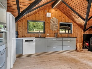 A modern kitchen with a wooden ceiling, built-in appliances, and a large window.