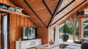 Una sala de estar moderna con techo de madera, un televisor de pantalla plana, un mueble blanco y un sofá.