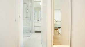 Une salle de bain moderne avec une douche à parois de verre, un meuble-lavabo blanc et un plancher en bois.