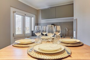 A dining table set with plates, glasses, and cutlery, with a view of the city through a window.