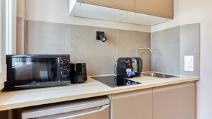 Een kleine keuken met een magnetron, koffiezetapparaat en een vaatwasser.