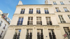 A multi-story building with a classical architectural style, featuring symmetrical windows and ornate balconies. - Charming Apartment Center of Paris (Paris)
