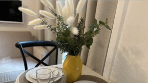 A dining table with a yellow vase of flowers, two plates, and two glasses. - Charming Apartment Center of Paris (Paris)
