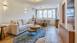 A modern living room with a sofa, round coffee table, and dining area with chairs. - Apartment in the Center of Paris (Paris)