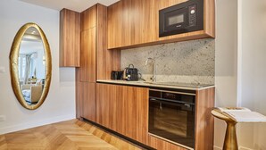 A modern kitchen with wooden cabinetry, a built-in microwave, a coffee machine, and a dishwasher. - Apartment in the Center of Paris (Paris)