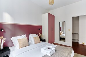 A modern bedroom with a large bed, a wardrobe, a nightstand, and a mirror. - Sublime 3 Bedroom Flat Palais Royal Bourse (Paris)