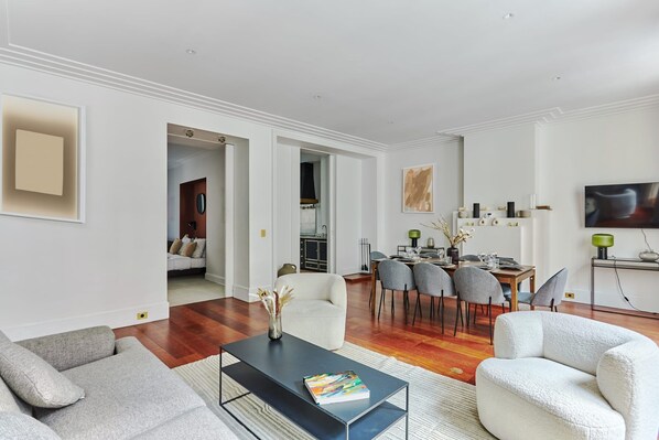 A modern living room with a sofa, coffee table, and dining area with chairs. - Sublime 3 Bedroom Flat Palais Royal Bourse (Paris)
