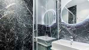 A modern bathroom with a glass-enclosed shower, a white sink, and a large mirror. - Sublime 3 Bedroom Flat Palais Royal Bourse (Paris)