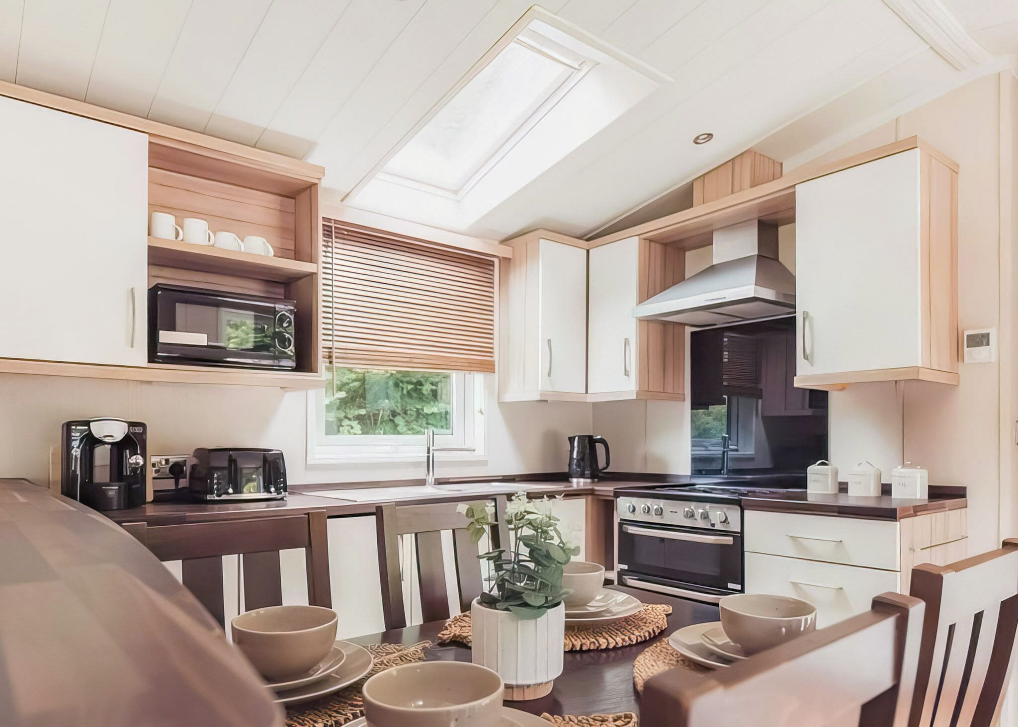 Une cuisine moderne dotée d’une verrière, d’appareils électroménagers intégrés et de meubles de rangement en bois.