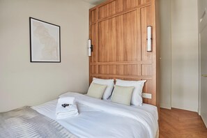A neatly made bed with white linens, a wooden headboard, and a framed artwork on the wall. - New Apartment Center of Paris/le Marais (Paris)