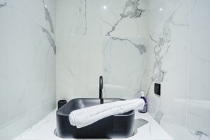 A modern bathroom with a black sink, white marble tiles, and a towel hanging on the side. - New Flat Terrace Centre de Paris Bourse (Paris)