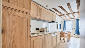 A modern kitchen with wooden cabinets, a built-in oven, and a dining area with a table and chairs. - New Flat Terrace Centre de Paris Bourse (Paris)
