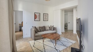 Moderni olohuone, jossa on sohva, sohvapöytä ja taideteos seinällä.