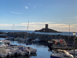 A marina with boats docked, a rocky breakwater, and a tower on a small island in the background. - Nice Paladian Villa in ST RAPHAEL, Boulouris, with simming-pool ,near beaches. (Saint-Raphaël)