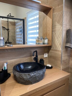 Une salle de bain avec un lavabo en pierre, un miroir, un porte-serviettes et des articles de toilette.