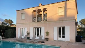 Un edificio de dos pisos con piscina, mobiliario exterior y un patio cubierto.