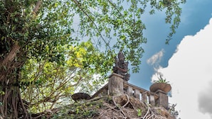 A stone structure with a staircase on a cliff, surrounded by dense foliage and tree roots. - Tropical Villa Sinar Maluku (Ungasan)