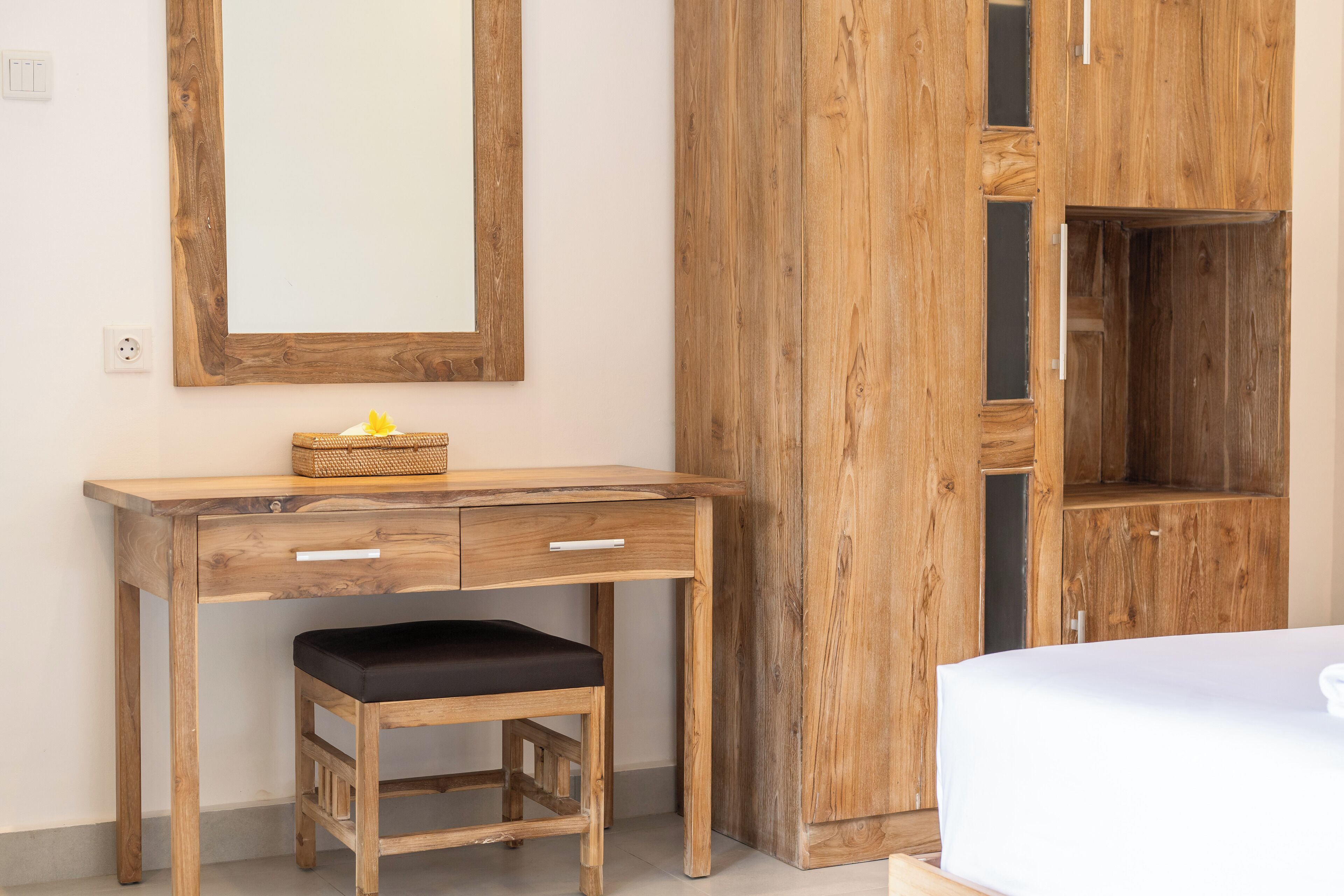 A wooden desk with drawers and a bench, a mirror, and a wardrobe with multiple compartments.