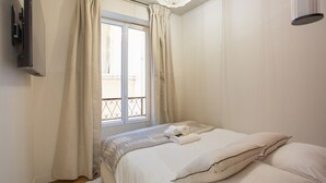 Un dormitorio con cama, cortinas, ventana y lámpara en el techo.