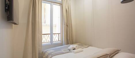 A bedroom with a bed, curtains, a window, and a ceiling light fixture.
