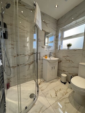 Un baño moderno con ducha acristalada, lavamanos blanco y retrete.
