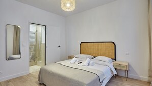 Ein modernes Schlafzimmer mit Bett, Nachttischen, einem Spiegel und einem begehbaren Kleiderschrank.