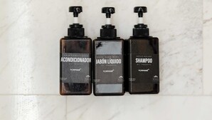 Tre flaskor hårinpackning, duschkräm och schampo placerade på en marmoryta.