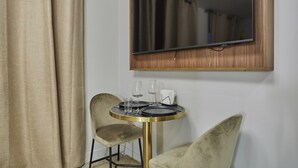 Ein Zimmer mit einem runden Tisch, zwei Stühlen, einem Spiegel und einem Vorhang.