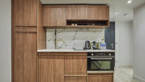 Eine kompakte Küche mit Holzausstattung, einer Marmor-Spritzschutzwand und einem eingebauten Backofen.