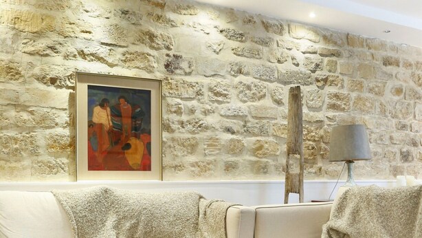 A modern living room with a stone wall, a white sofa, a wooden coffee table, and a lamp. - Superb Terrace Apart Champs Elysees Eiffel Tower (Paris)