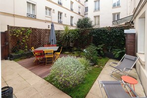 A patio with a table and chairs, a small garden, and two lounge chairs. - Superb Terrace Apart Champs Elysees Eiffel Tower (Paris)