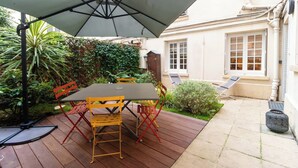 An outdoor patio with a table and chairs, surrounded by greenery and a building in the background. - Superb Terrace Apart Champs Elysees Eiffel Tower (Paris)