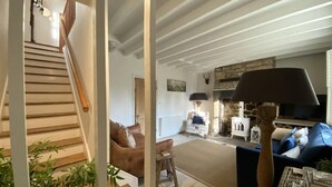 A cozy living room with a staircase, a fireplace, and a comfortable seating area.