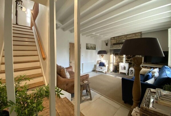 Un salon chaleureux avec un escalier, une cheminée et un coin salon confortable.