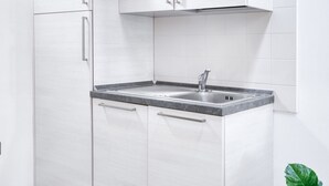 A modern kitchen with white cabinetry, a granite countertop, and a stainless steel sink.