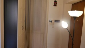 A hotel room with a door, a curtain, a wall-mounted phone, a light fixture, and a small decorative item. - Lovely apartment by the sea in Rome (Ostia Lido) (Lido di Ostia)