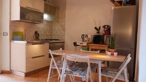 A compact kitchen with a dining table, chairs, and a refrigerator. - Lovely apartment by the sea in Rome (Ostia Lido) (Lido di Ostia)
