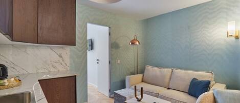 Un espacio habitable compacto con cocina, un sofá, una mesa de centro y una lámpara.