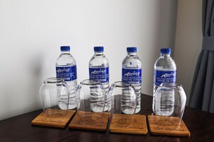 Una mesa con seis botellas de agua Aquashill y cuatro vasos en posavasos de madera.