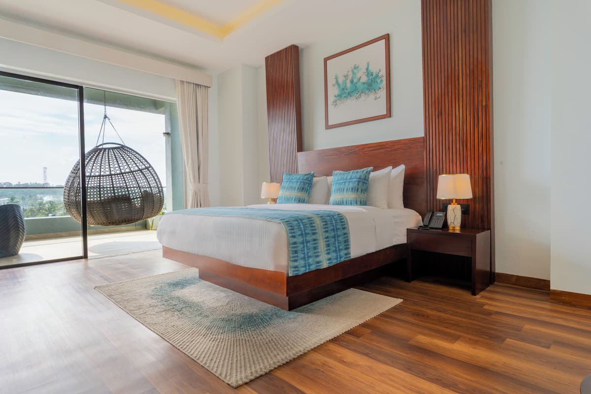 A modern hotel room with a large bed, a hanging chair, a wooden headboard, a nightstand, and a view of the city.